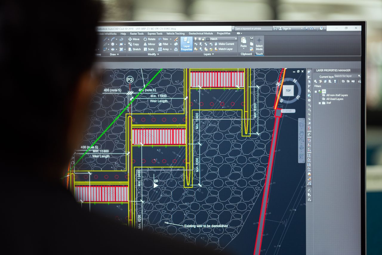 The Art of Drawing Readers In: Your attractive post title goes here A civil engineer working on a weir design using CAD software on a computer screen in an office setting.